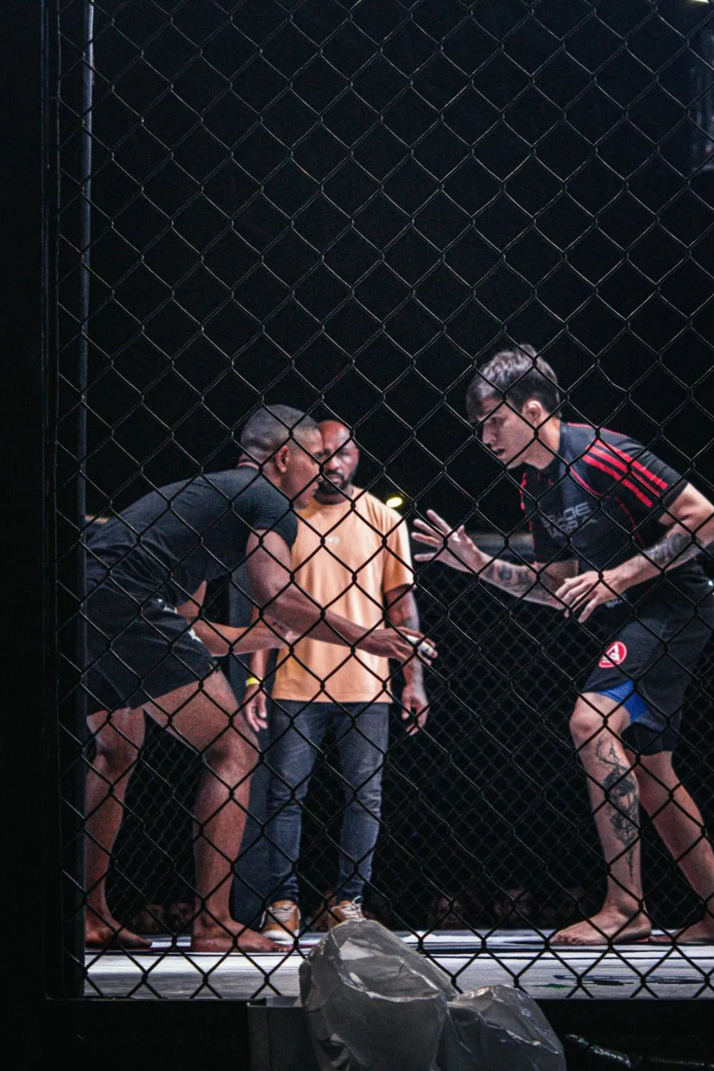 Rozhodčí mezi dvěma zápasníky MMA v kleci před zápasem